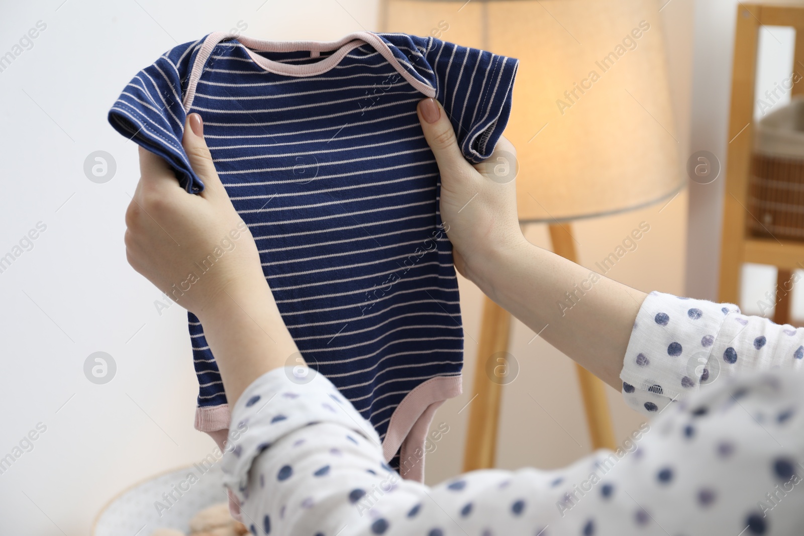 Photo of Woman with baby clothes at home, closeup