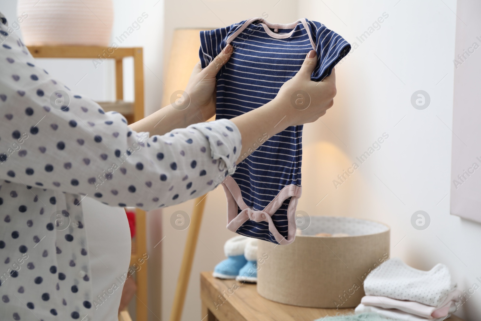 Photo of Woman with baby clothes at home, closeup