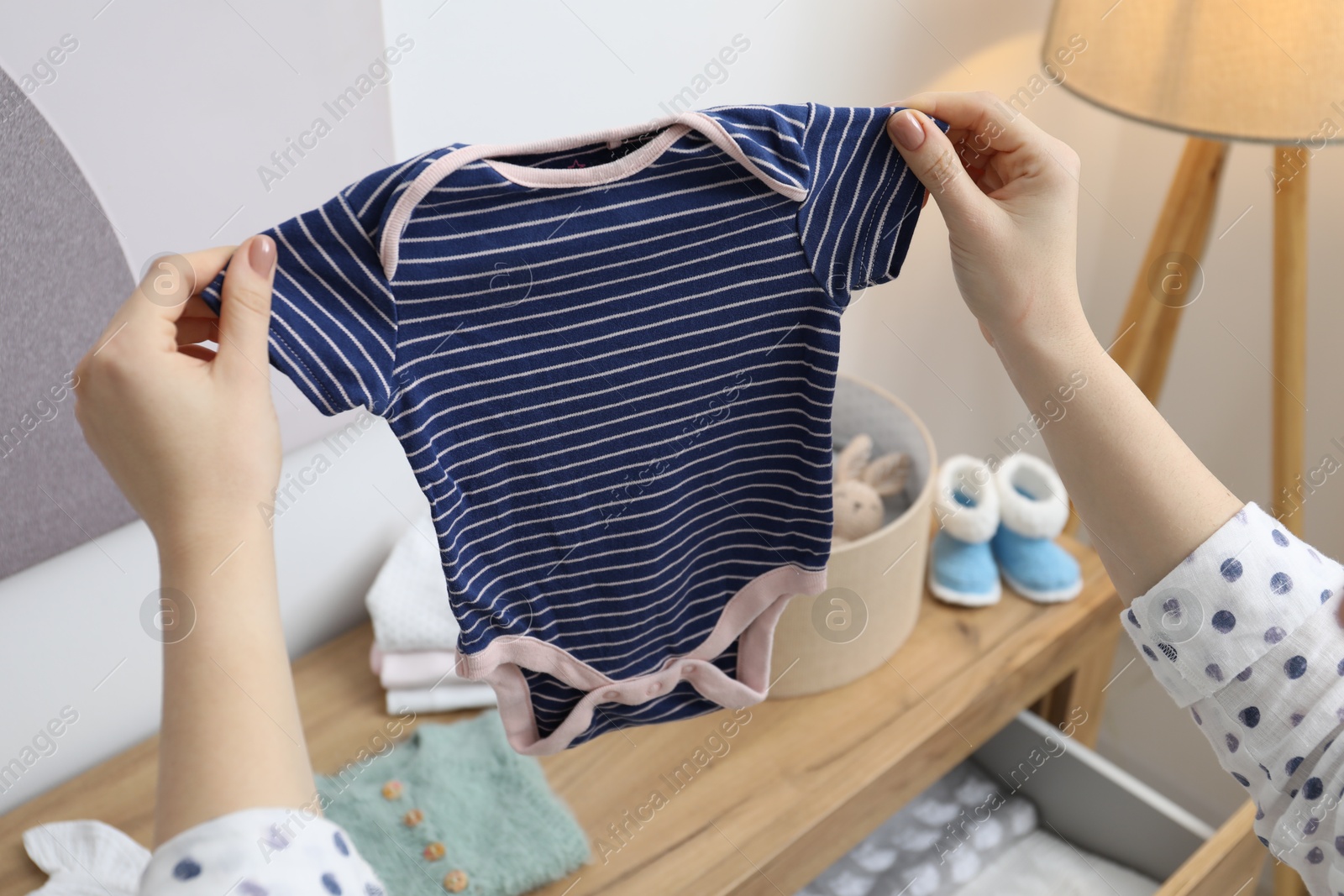 Photo of Woman with baby clothes at home, closeup