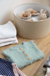 Photo of Baby clothes on wooden chest of drawers indoors, closeup