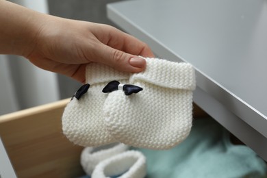 Photo of Woman with baby socks at home, closeup