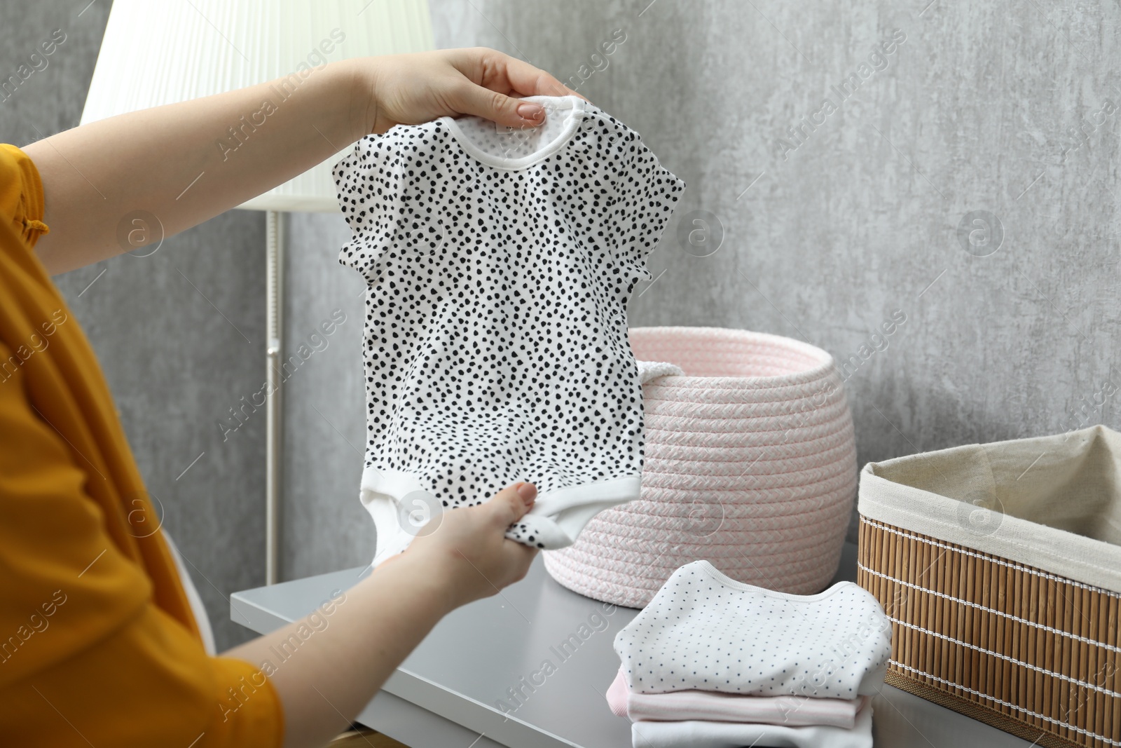 Photo of Woman with baby clothes at home, closeup