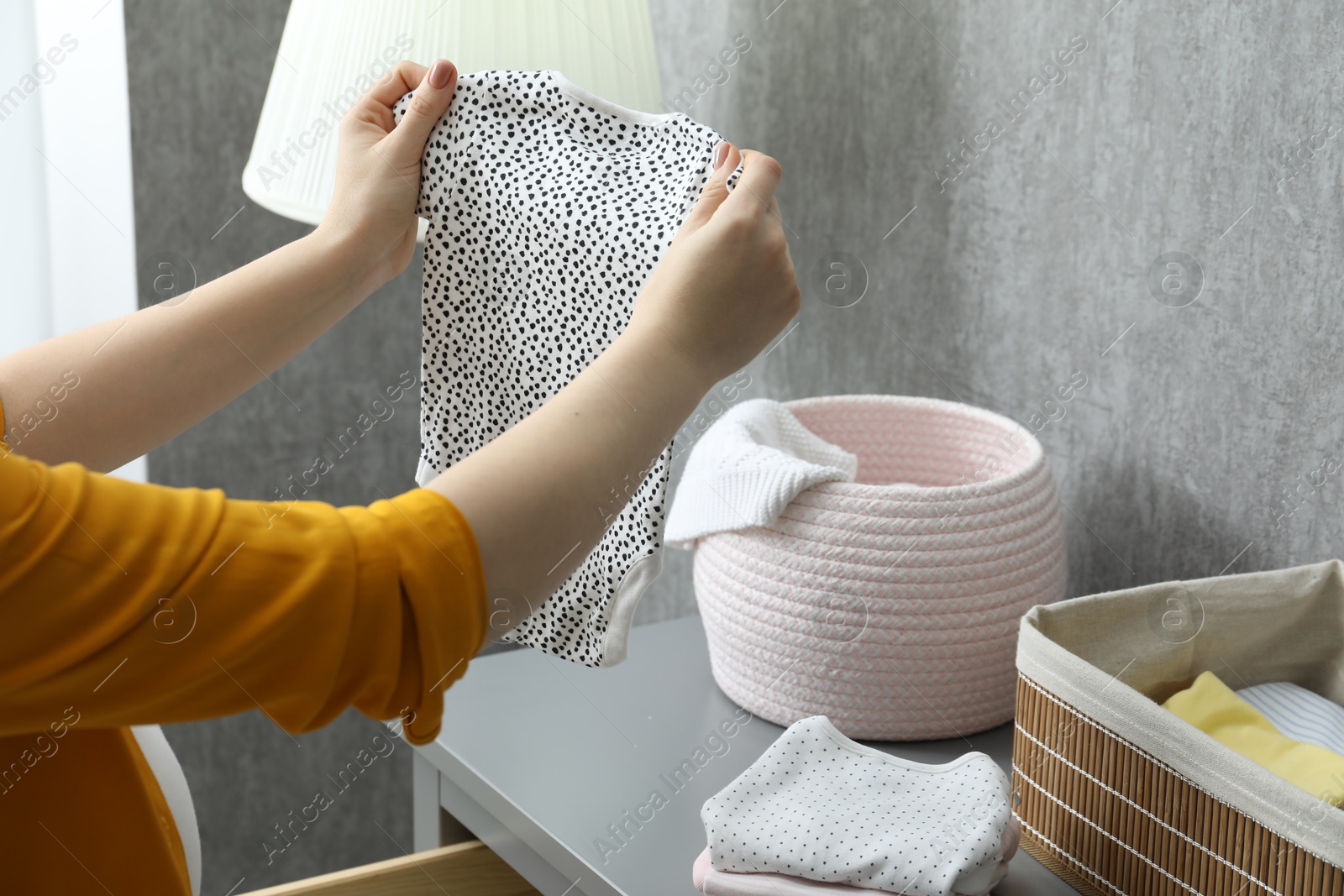 Photo of Woman with baby clothes at home, closeup