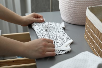 Photo of Woman folding baby clothes at home, closeup