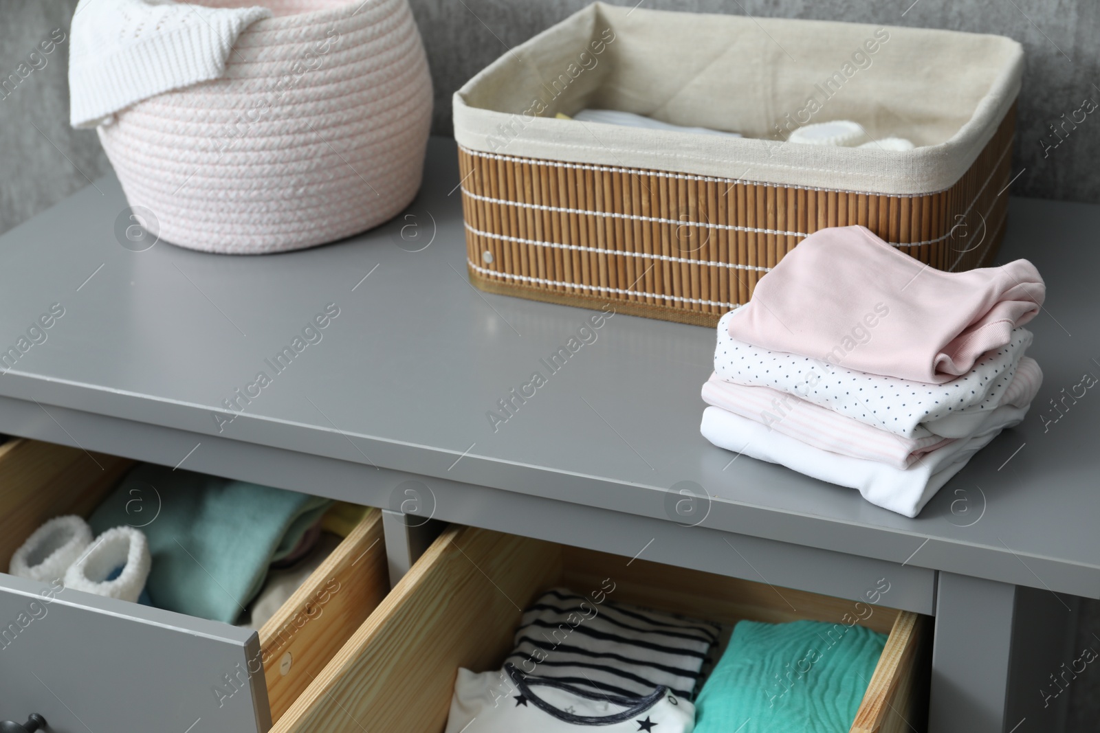 Photo of Baby clothes on gray chest of drawers indoors