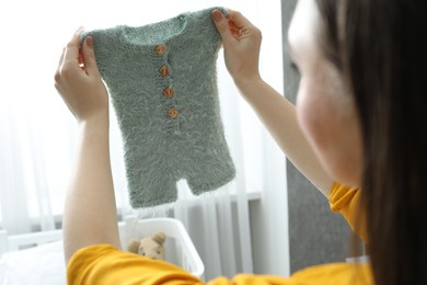 Photo of Woman with baby clothes at home, closeup