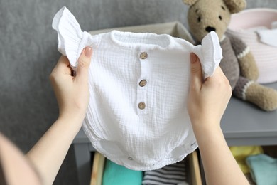 Photo of Woman with baby clothes at home, closeup