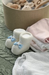 Photo of Baby clothes and box with toys on green blanket, closeup