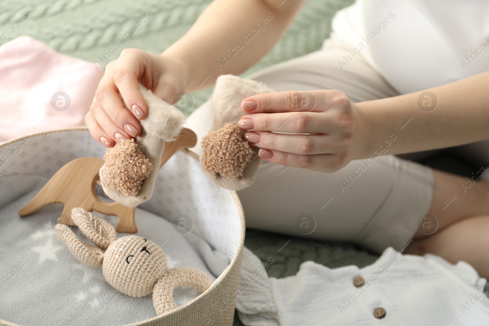 Photo of Pregnant woman with baby socks on bed at home, closeup