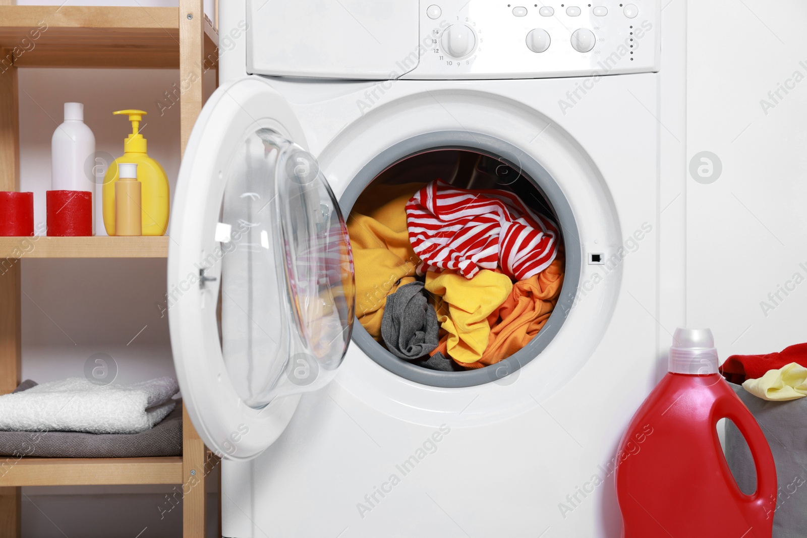 Photo of Washing machine and detergent near white wall