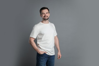 Photo of Man in blank white t-shirt on grey background. Mockup for design