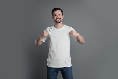 Photo of Man in blank white t-shirt on grey background. Mockup for design