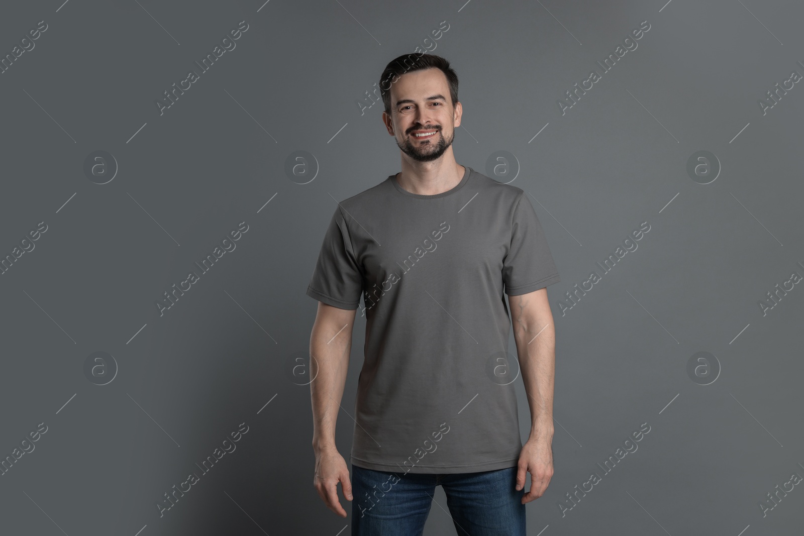 Photo of Man in blank t-shirt on grey background. Mockup for design