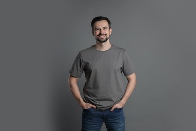 Photo of Man in blank t-shirt on grey background. Mockup for design