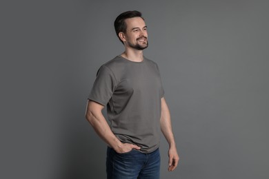 Photo of Man in blank t-shirt on grey background. Mockup for design