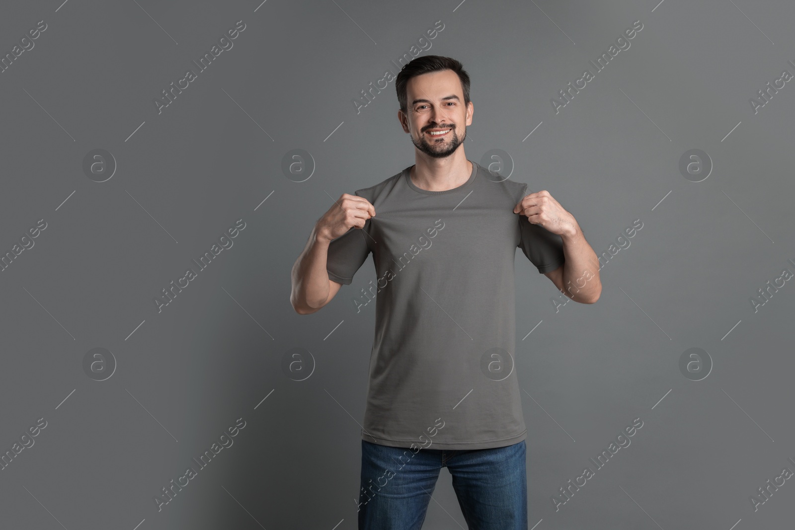 Photo of Man in blank t-shirt on grey background. Mockup for design