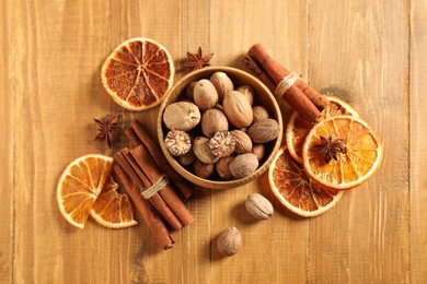 Photo of Different spices and dried orange slices on wooden table, flat lay. Christmas season