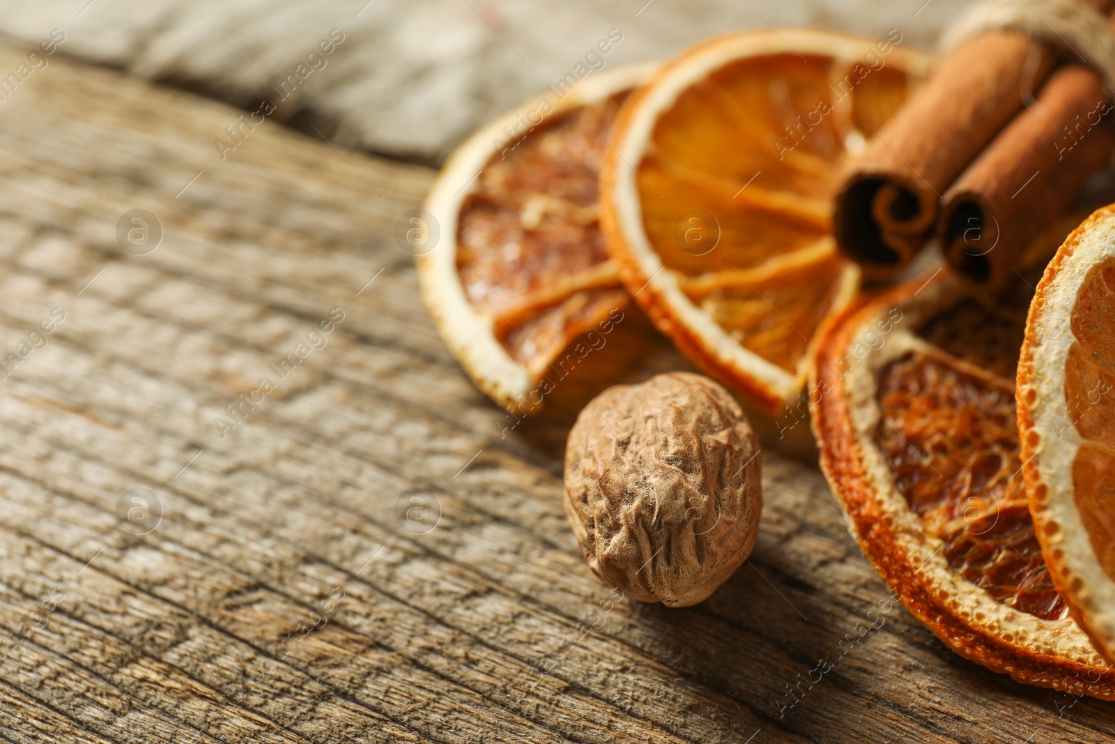 Photo of Different spices and dried orange slices on wooden table, closeup with space for text. Christmas season