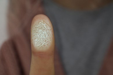 Image of Woman pressing finger to surface showing friction ridges pattern, closeup. Scanning fingerprint