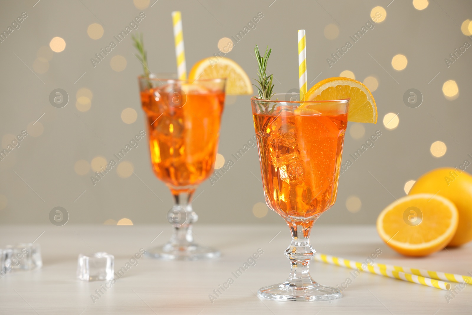 Photo of Tasty Christmas cocktail in glasses on white wooden table against blurred lights