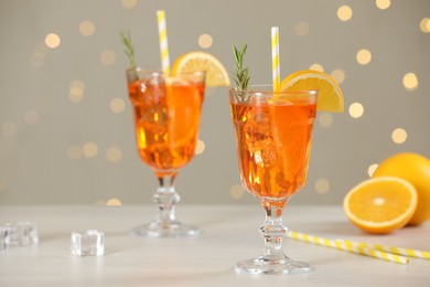 Photo of Tasty Christmas cocktail in glasses on white wooden table against blurred lights