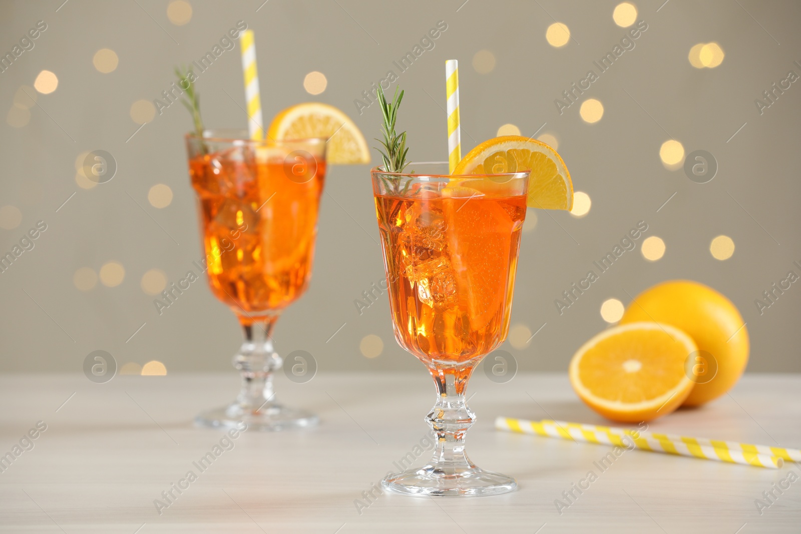 Photo of Tasty Christmas cocktail in glasses on white wooden table against blurred lights