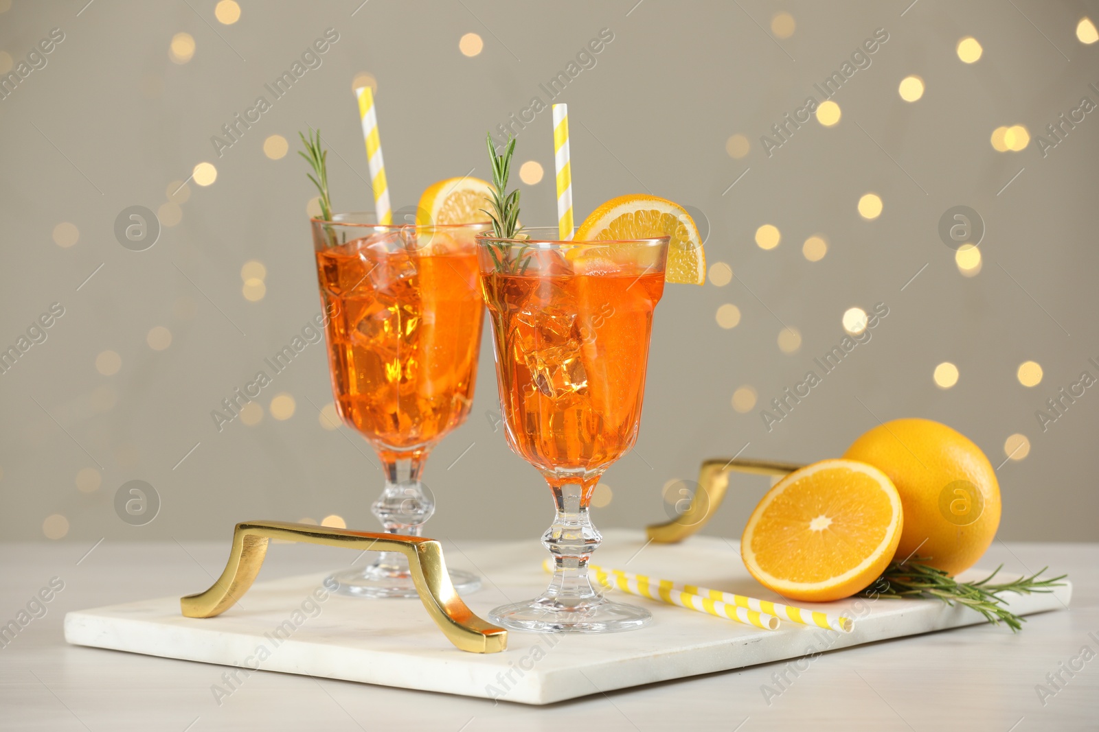 Photo of Tasty Christmas cocktail in glasses on white wooden table against blurred lights