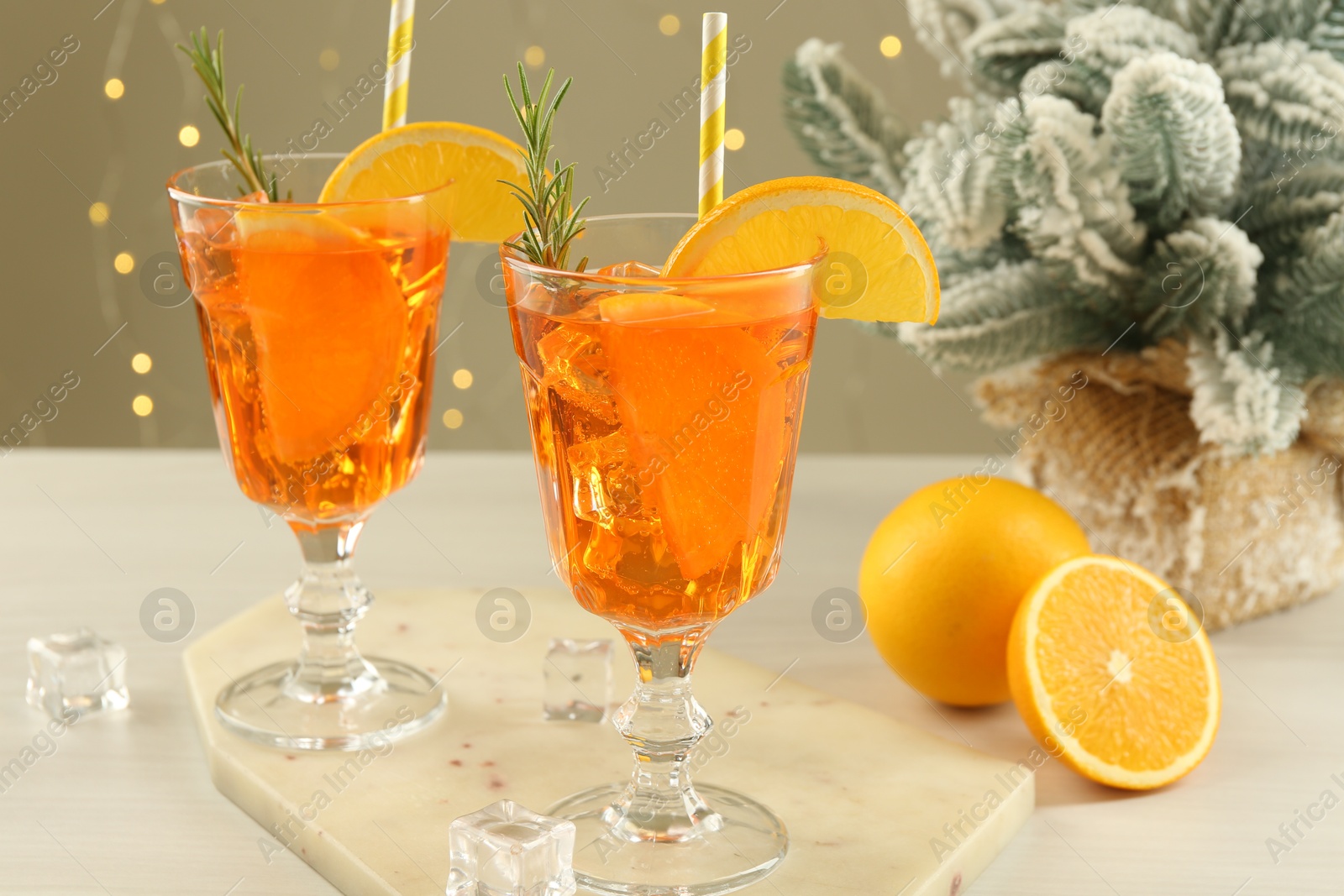 Photo of Tasty Christmas cocktail in glasses and fir tree branches on white wooden table against blurred lights, closeup