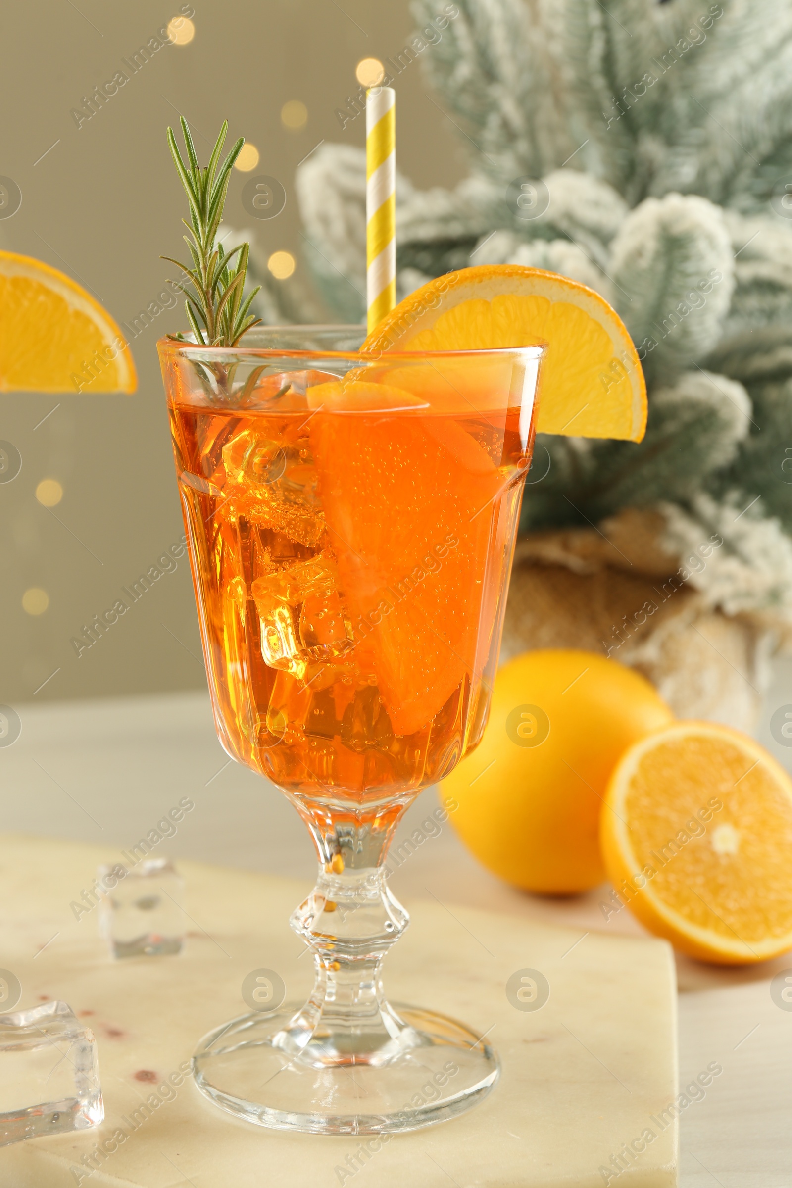 Photo of Tasty Christmas cocktail in glass and fir tree branches on white wooden table against blurred lights, closeup