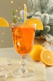 Photo of Tasty Christmas cocktail in glass and fir tree branches on white wooden table against blurred lights, closeup