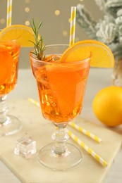 Photo of Tasty Christmas cocktail in glasses and fir tree branches on white wooden table against blurred lights, closeup