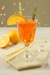 Photo of Tasty Christmas cocktail in glass on white wooden table against blurred lights