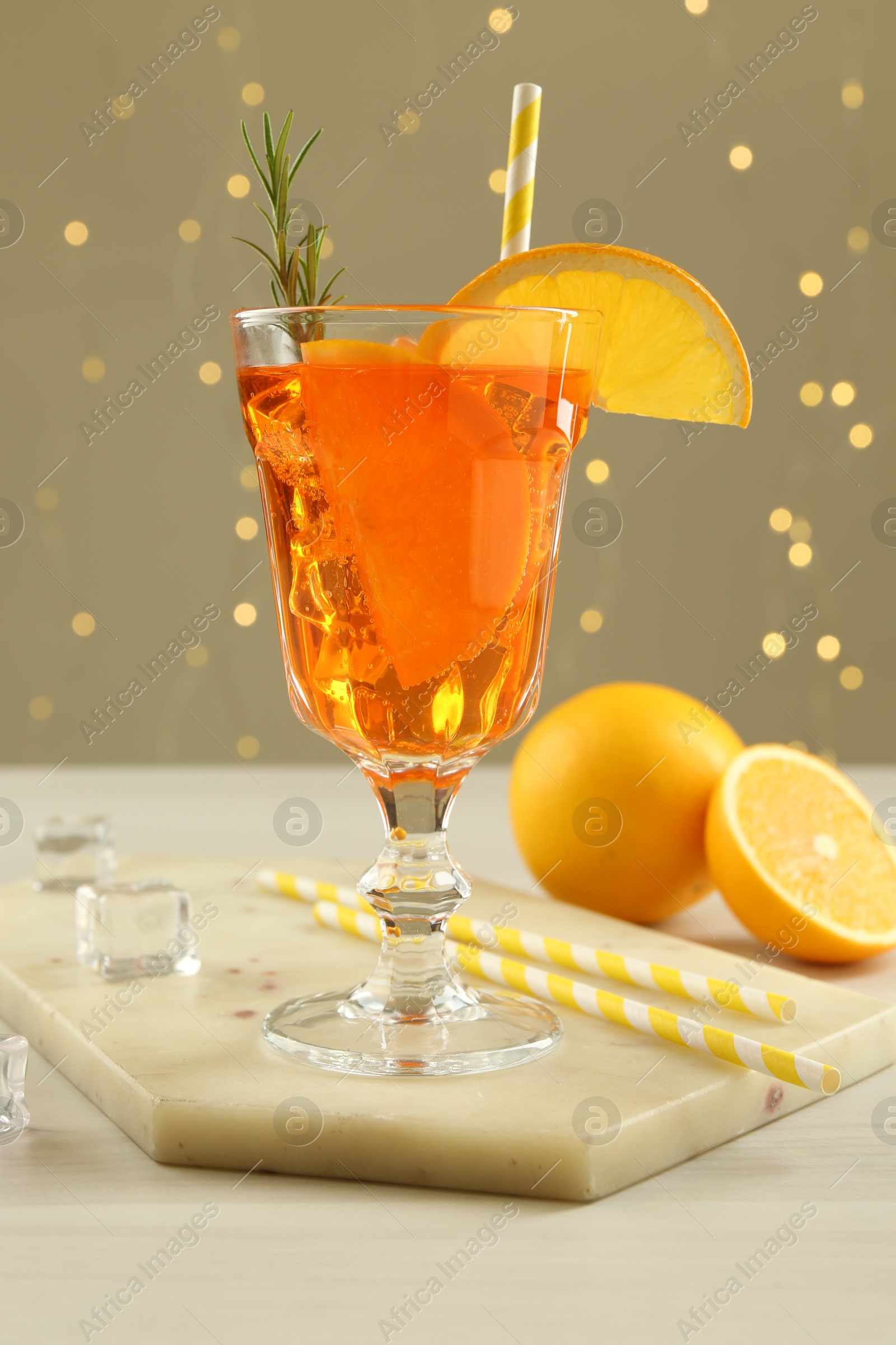 Photo of Tasty Christmas cocktail in glass on white wooden table against blurred lights