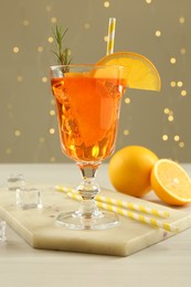 Photo of Tasty Christmas cocktail in glass on white wooden table against blurred lights