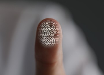 Image of Man pressing finger to surface showing friction ridges pattern, closeup. Scanning fingerprint