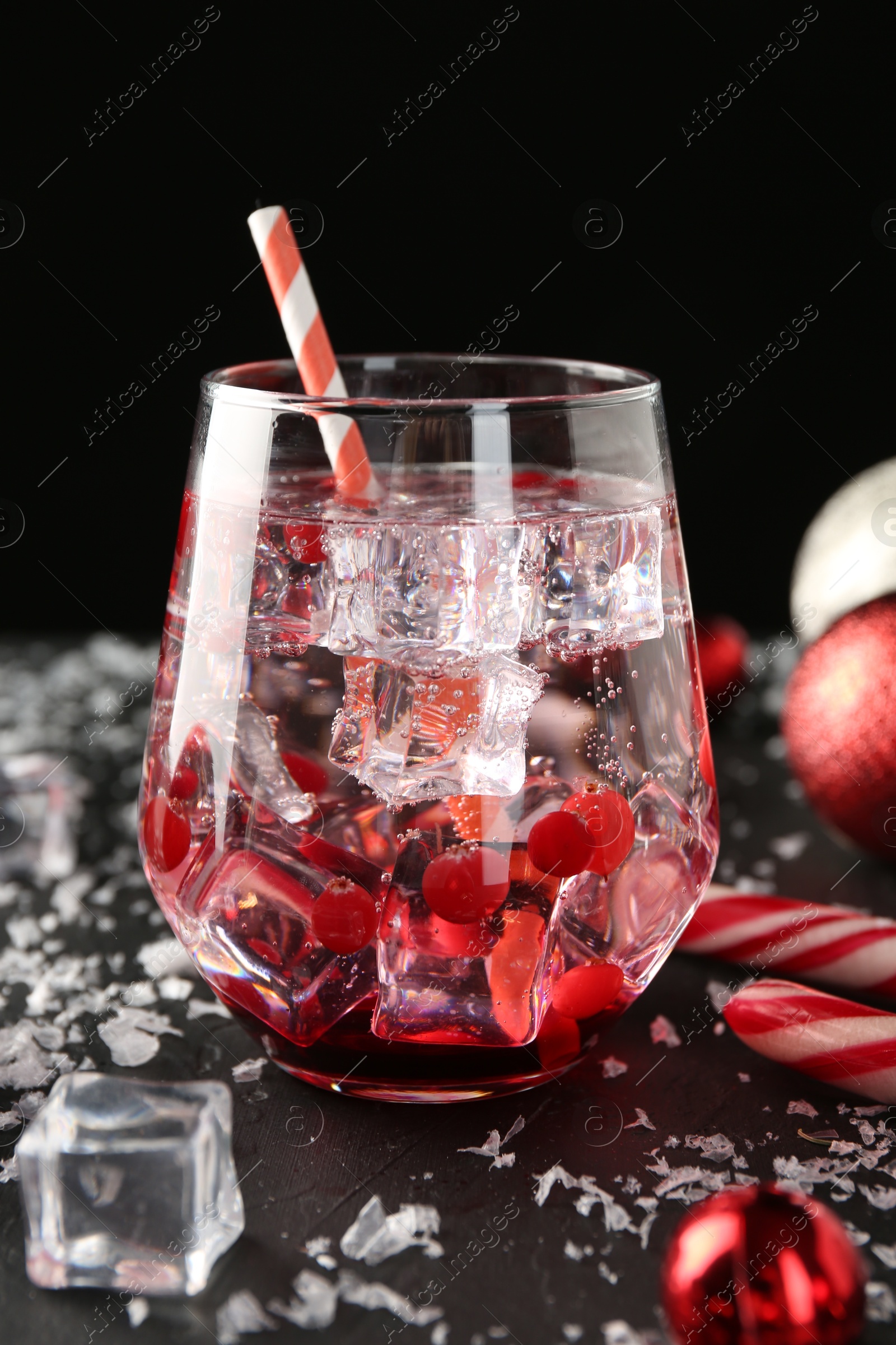 Photo of Tasty Christmas cocktail in glass, ice and decor on black table, closeup