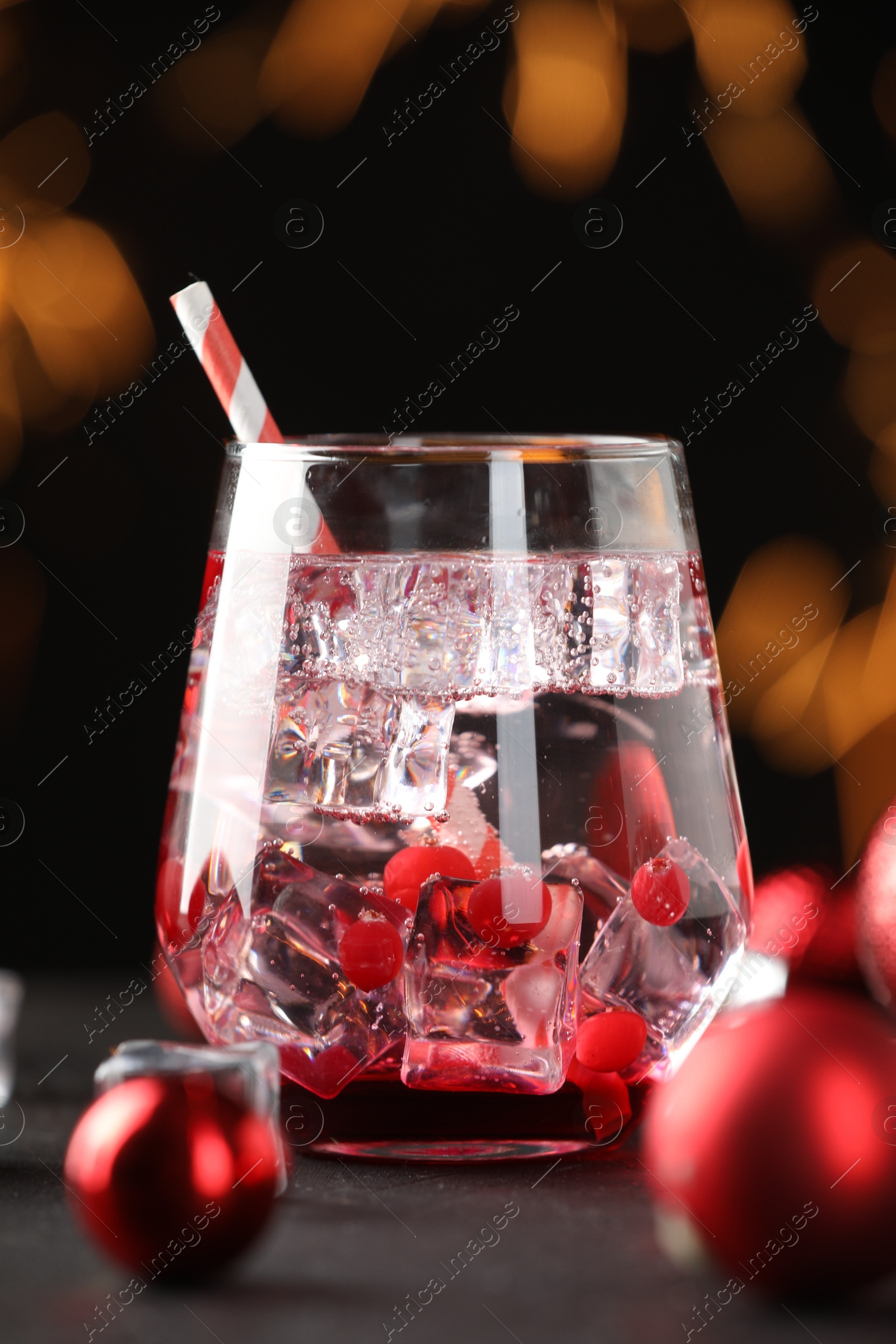 Photo of Tasty Christmas cocktail in glass and decor on table against dark background with blurred lights, closeup