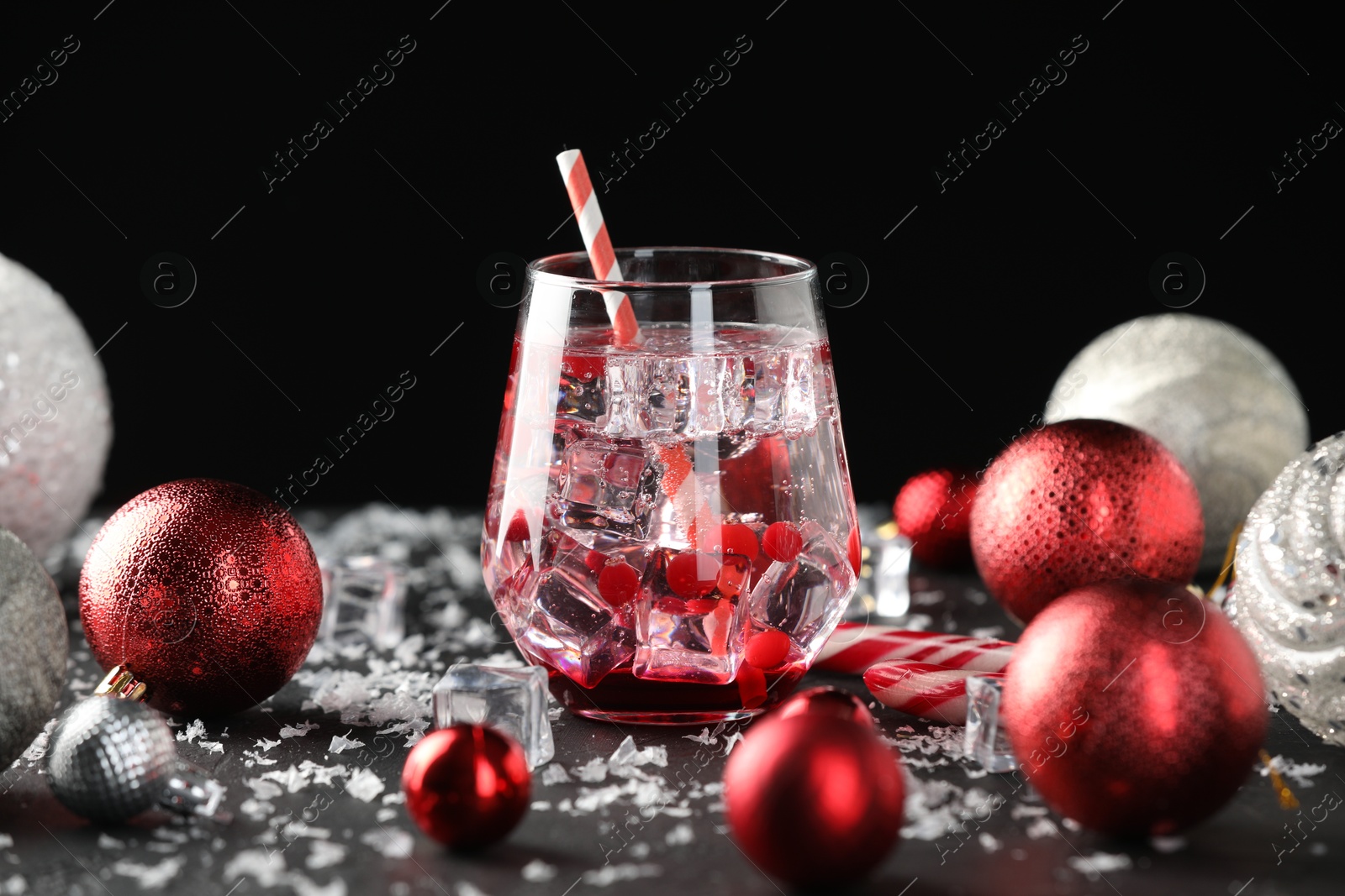 Photo of Tasty Christmas cocktail in glass, ice and decor on black table