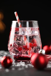 Photo of Tasty Christmas cocktail in glass, ice and decor on table, closeup