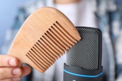 Photo of Woman making ASMR sounds with microphone and wooden comb, closeup