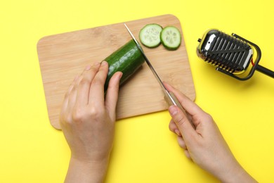 Photo of Woman making ASMR sounds with microphone and cucumber on yellow background, top view