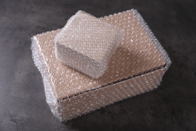 Photo of Cardboard boxes covered with bubble wrap on dark grey table