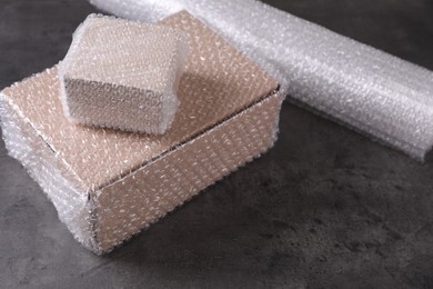 Photo of Cardboard boxes with bubble wrap on dark grey table