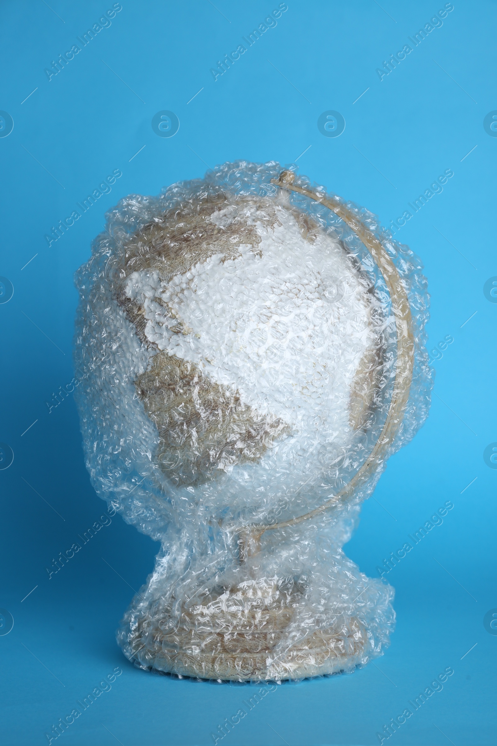 Photo of Globe packed in bubble wrap on turquoise background. Environmental conservation