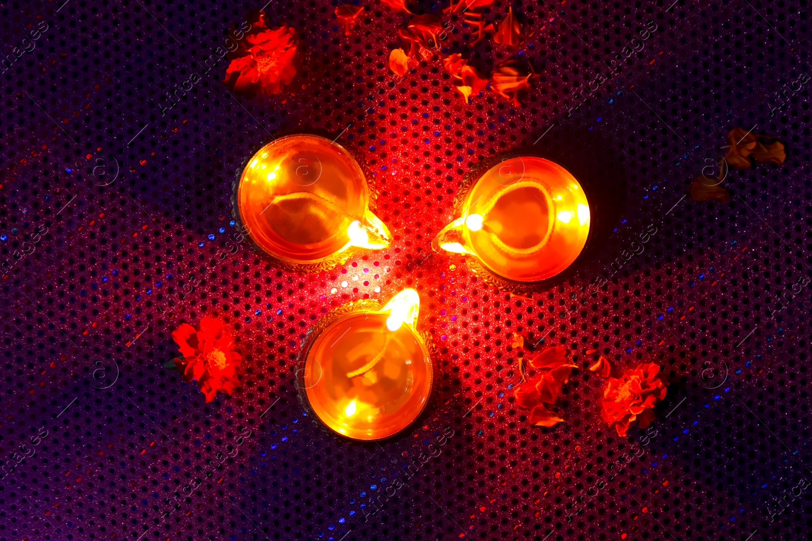 Photo of Diwali celebration. Diya lamps and beautiful flowers on dark background, top view