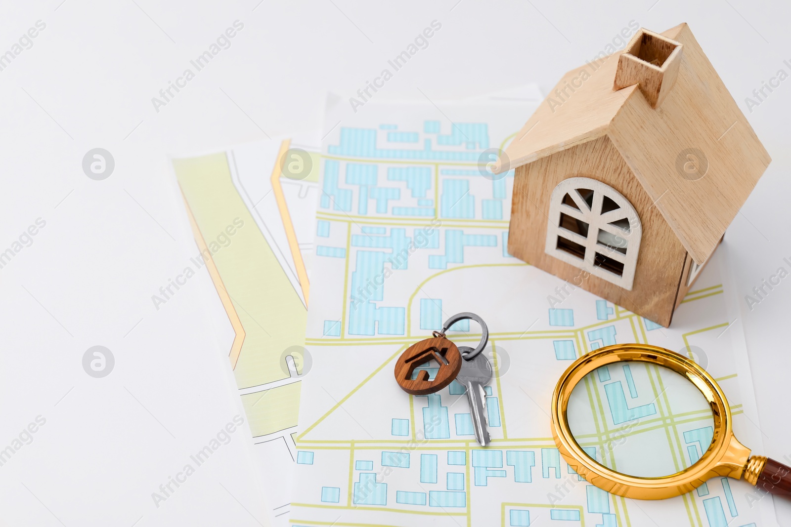 Photo of House hunting. Maps, key. magnifying glass and house figure on white table, space for text