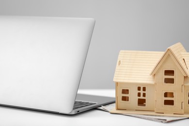 Photo of House hunting. Papers, laptop and house figure on white table