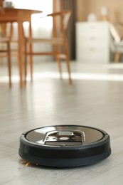 Photo of One robotic vacuum cleaner on wooden floor in living room. Space for text