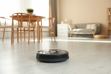 Photo of One robotic vacuum cleaner on wooden floor in living room. Space for text