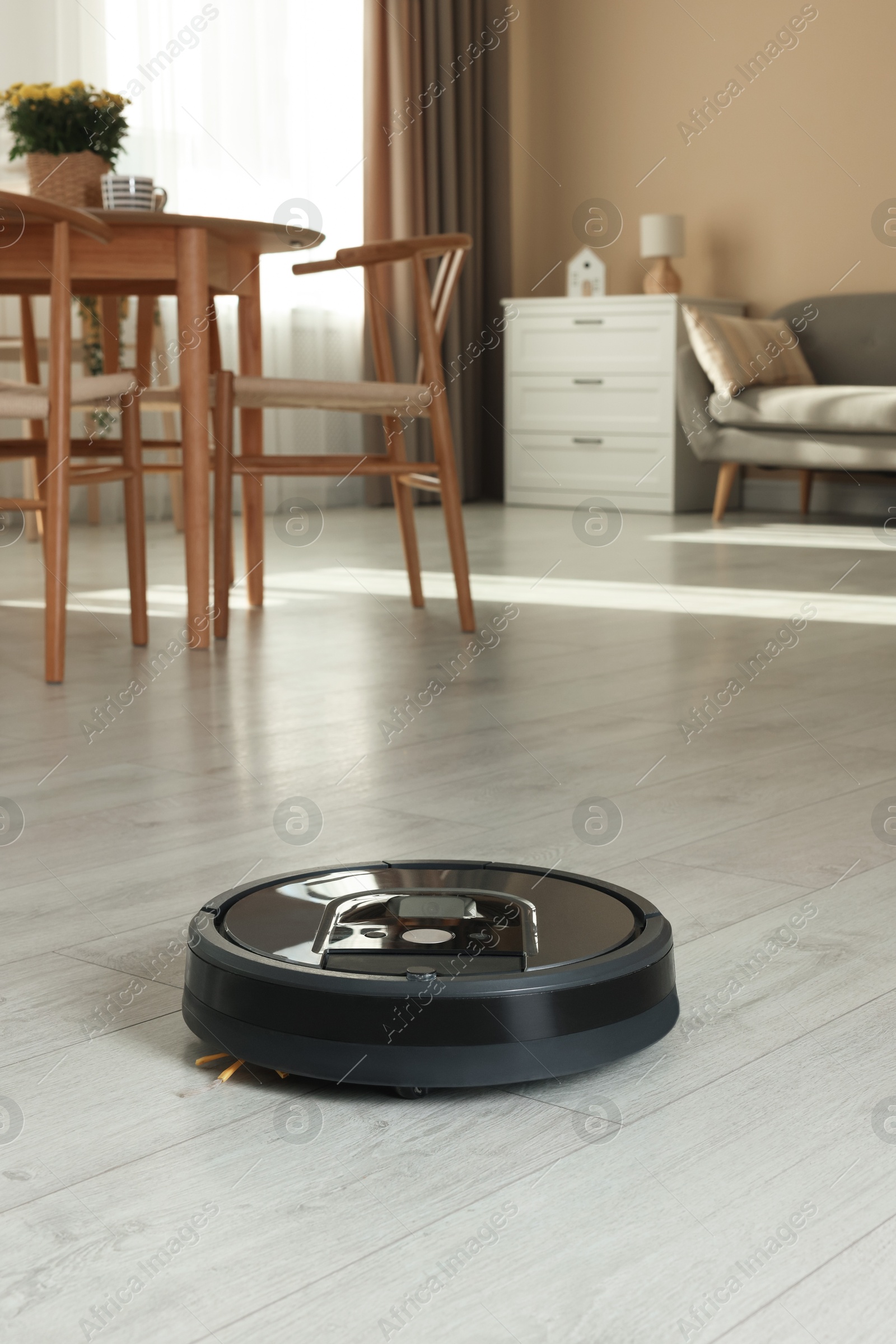 Photo of One robotic vacuum cleaner on wooden floor in living room